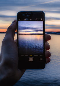 Person Holding Post-2014 Iphone Taking a Photo of Body of Water thumbnail