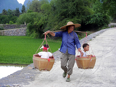 woman carrying basket with two children during daytime thumbnail