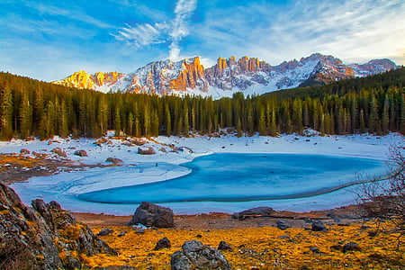body of water in middle of pine trees under blue and white sunny sky during daytime thumbnail
