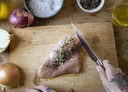 Person Slicing Raw Meat With Pepper on Chopping Board Beside Spices thumbnail
