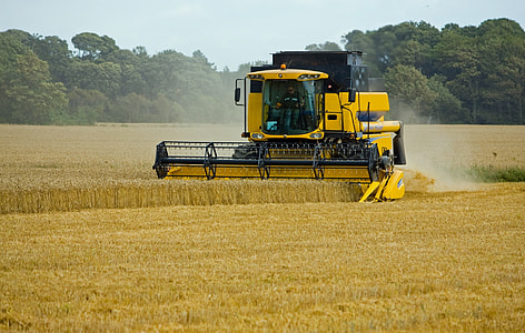yellow harvester machine on green grass field thumbnail