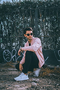 man partial kneeling looking to his left in front of gate thumbnail