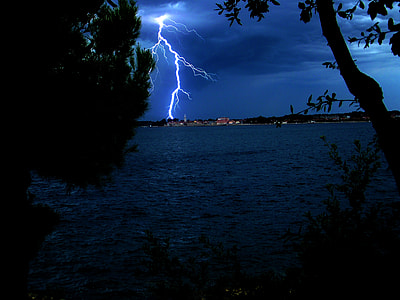 lightning strikes near high rise building on the other side of the lake thumbnail