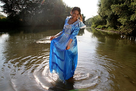 woman wearing blue dress standing on body of water during day time thumbnail