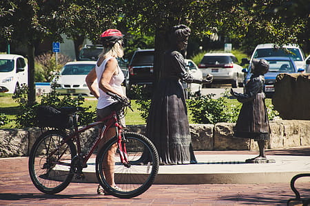 Woman Wearing White Tank Top Holding Red Hardtail Mountain Bike thumbnail