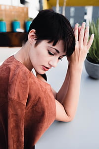 woman leaning on table near plant thumbnail