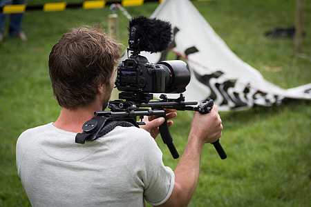 man in white shirt recording video using black DSLR camera during daytime thumbnail