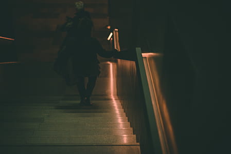low light photography of person walking downstairs thumbnail