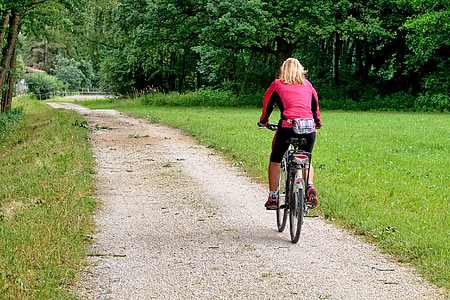 woman cycling on pathway during daytime thumbnail