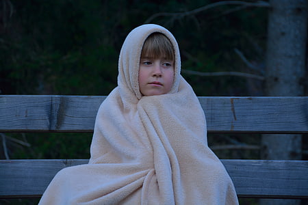 kid covered with blanket sitting on bench thumbnail