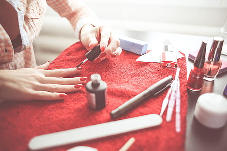 person's red nail polish on top of red textile thumbnail