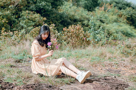 Woman Sitting on Ground and Holding Flower thumbnail