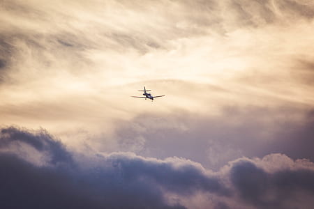airplane flying over grey cloudy skies thumbnail