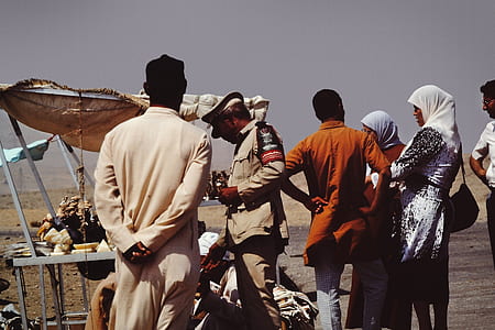 Group of People on Desert Beside Brown Tent thumbnail
