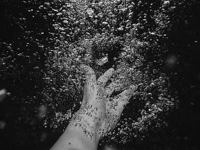 grayscale photography of person's hand in water thumbnail