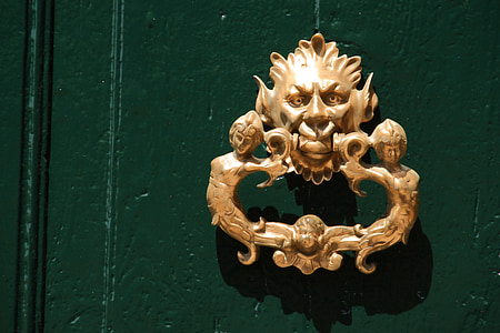 gold-colored door knocker on wall thumbnail