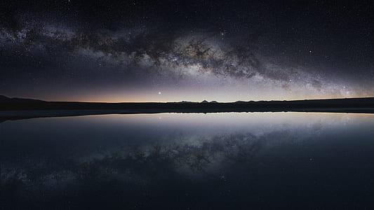silhouette of mountain in front of body of water under dark sky thumbnail