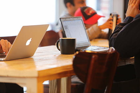 silver MacBook beside black ceramic mug on top of brown wooden table thumbnail