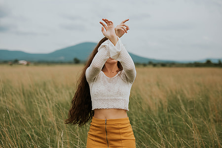 woman in white crop sweater and brown bottoms surrounded by grasses thumbnail