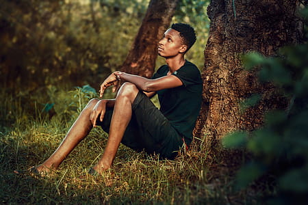 Man Seating Beside Tree Trunk thumbnail