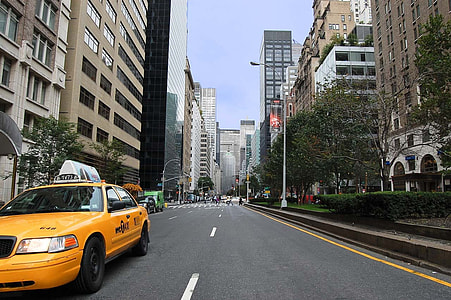yellow sedan on concrete road between high-rise buildings at daytime thumbnail