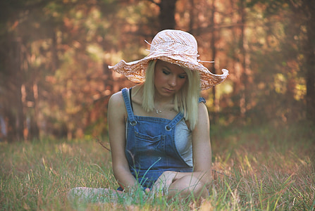 woman wearing pink beach hat sitting on green grass thumbnail