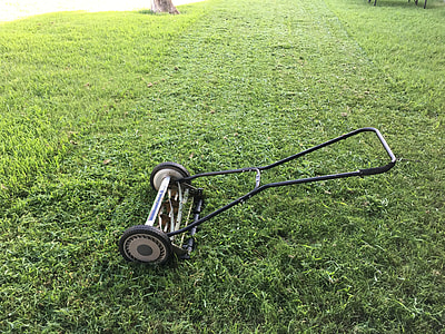 black reel mower on green grass lawn thumbnail