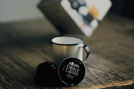 white cup beside coffee pods on top of table thumbnail