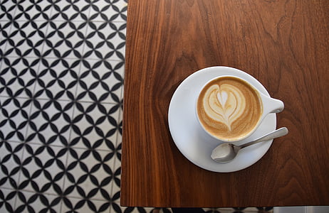 cappuccino filled teacup with saucer on top of table thumbnail