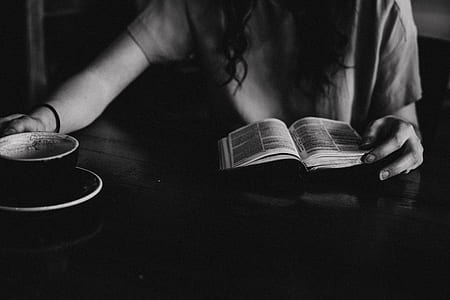woman sitting beside table with book and mug on top thumbnail