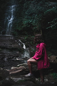 woman in pink jacket near waterfalls thumbnail