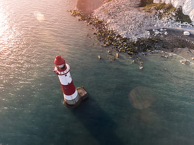 red and white lighthouse on a body of water thumbnail