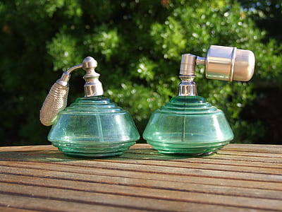 two green glass fragrance bottles on brown wooden table thumbnail