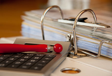gray desk calculator beside pile of papers thumbnail