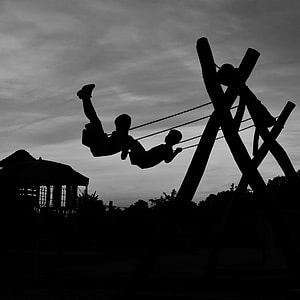 silhouette of two children in swing thumbnail