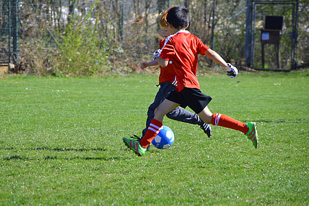 two boy playing soccer on green grass field during day time thumbnail