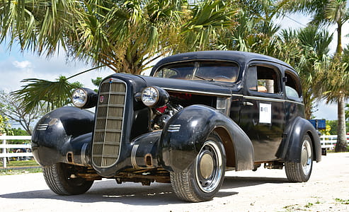vintage black vehicle parked near trees thumbnail