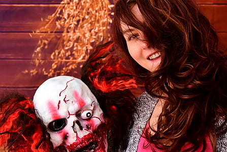 woman taking photo while holding Halloween mask thumbnail
