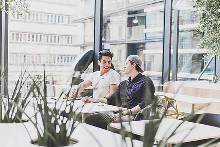 two men sitting beside each other near glass window thumbnail