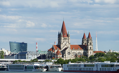 white and brown church near body of water and buildings thumbnail
