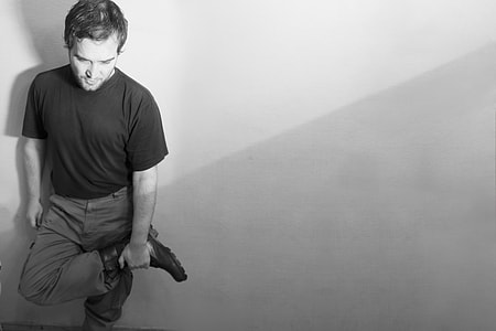 grayscale photo of man standing near wall thumbnail