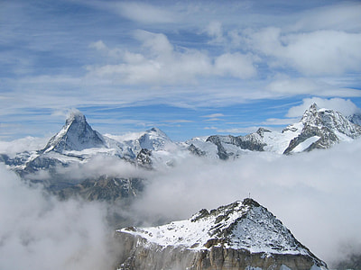 photography of mountains coated with snow under blue and white cloudy sky thumbnail