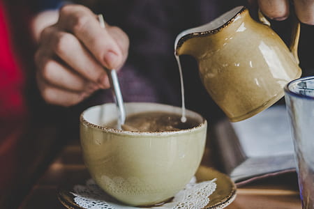 person pouring cream on teacup thumbnail