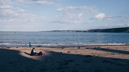 Person Walking Near Ocean Under White Sky thumbnail