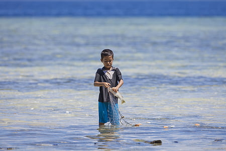 boy catching fish on body of water at daytime thumbnail