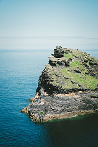 green hill beside body of water thumbnail
