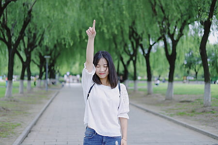 woman in white blouse pointing toward sky thumbnail