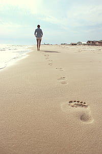 woman walking on seashore under white sky during daytime thumbnail