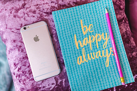 Blue notebook with a pink iPhone, headphones and a sweet bun thumbnail