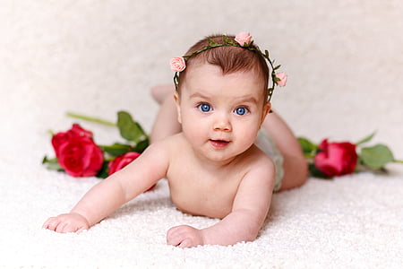 focus photography of baby near red roses thumbnail